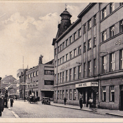Fotografie pro pohlednici pořízena někdy mezi červnem a červencem 1934, jak informuje transparent. Již jen Grand hotel, s vinárnou, lázněmi a s parfumerií s holírnou a česáním dam.